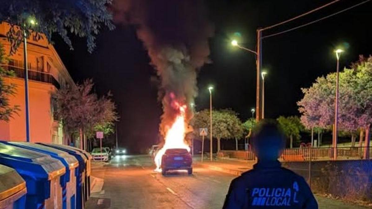 Un policía local, frente al coche incendiado.