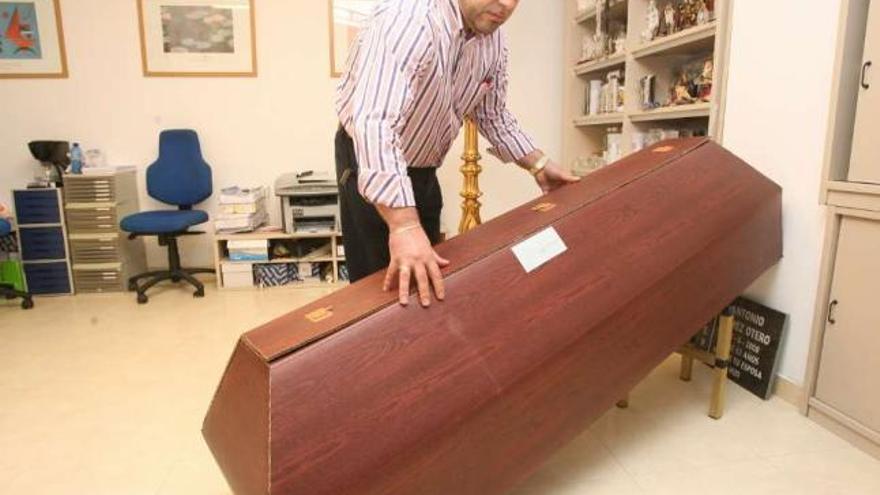 Un empleado de una funeraria gallega muestra un ataúd de cartón. / jesús de arcos