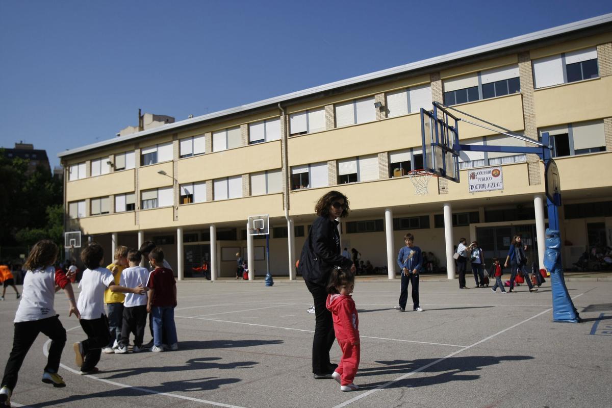 Unos niños jugando en el recreo del colegio público Doctor Azúa, con su profesora y una niña en primer plano