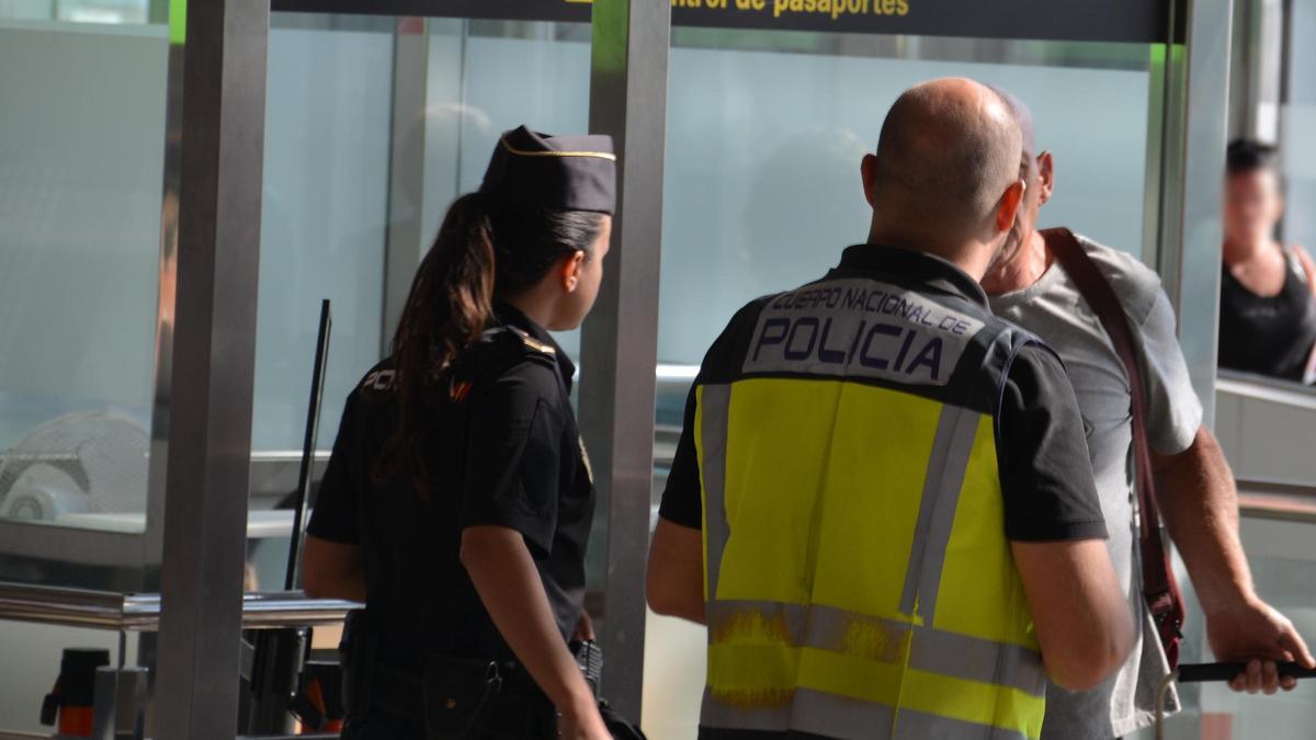 Agentes de la Policía Nacional interrogan al presunto traficante antes de detenerlo, en el control de pasajeros de Manises.