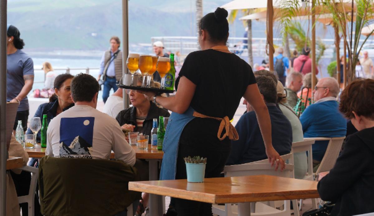 Una camarera atiende la terraza de un bar en el paseo de Las Canteras.