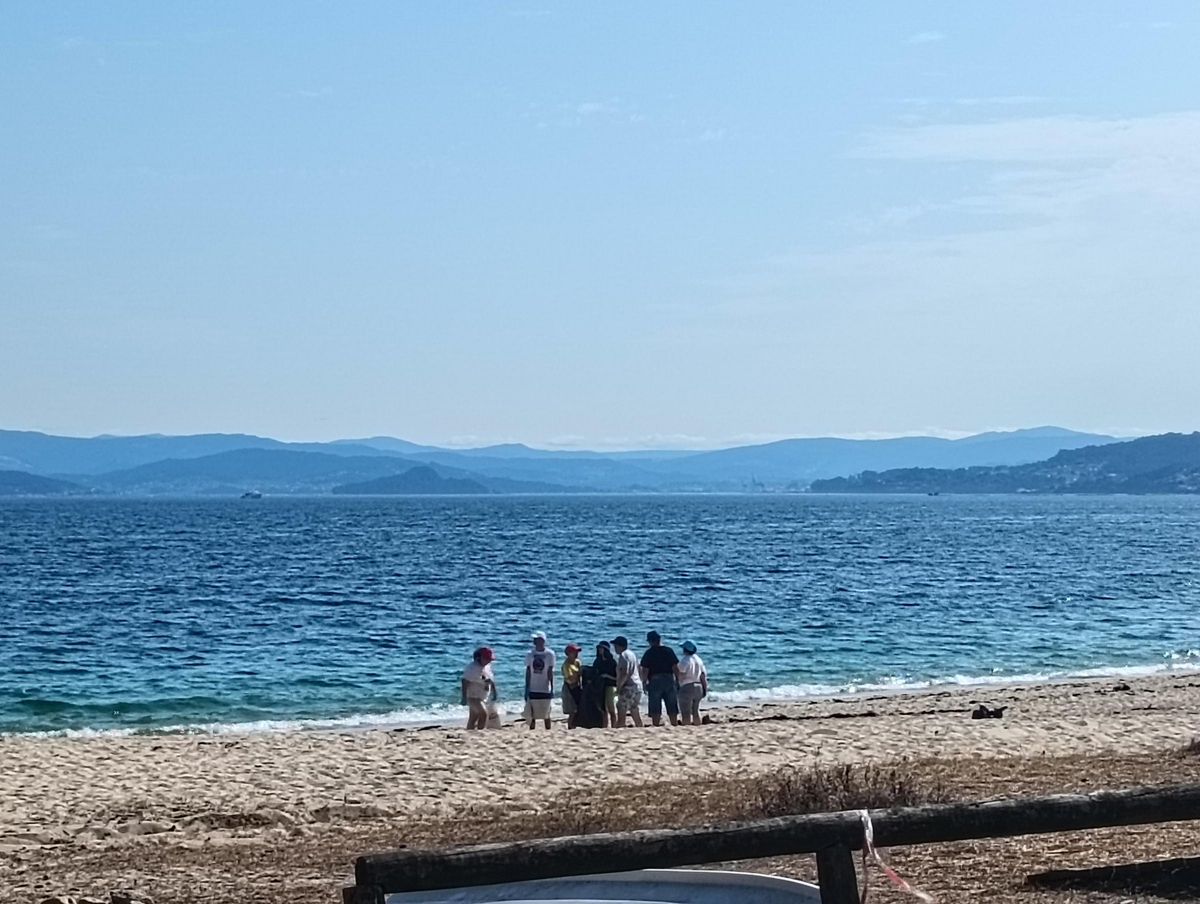 La acción de limpieza en la playa de Mourisca por parte de usuarios de la Asociación Juan XXIII.