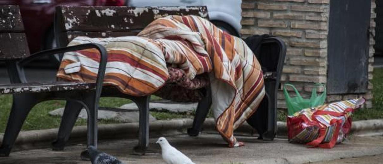 Una persona sin hogar reposa en uno de los bancos del parque de Canalejas.