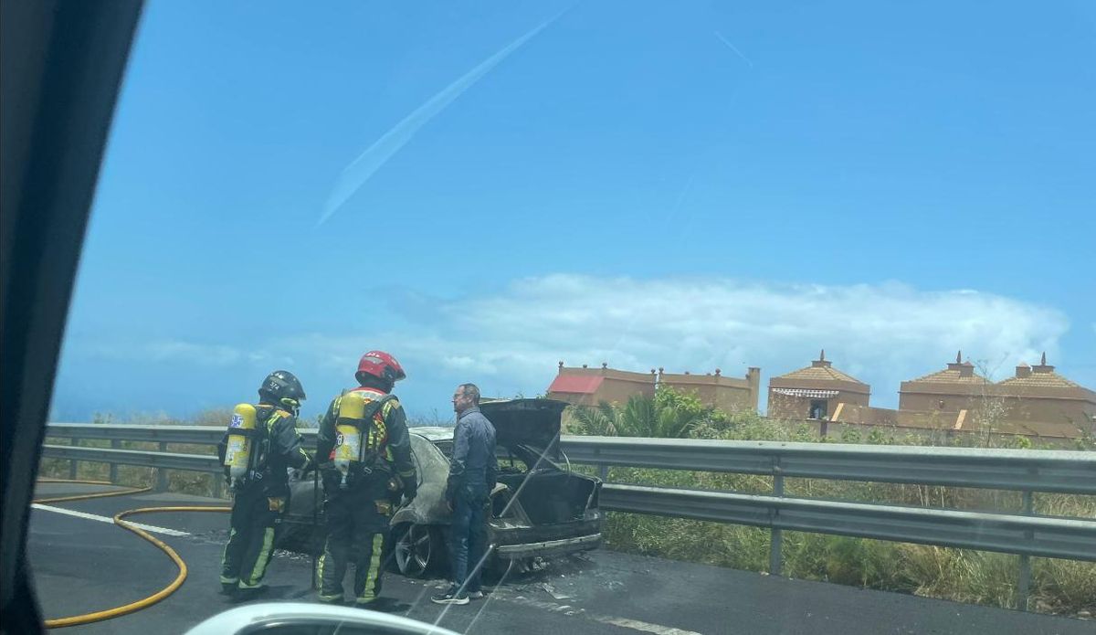 Los bomberos, junto al vehículo calcinado.