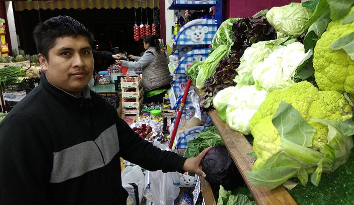 Éverson Fernández e Ibeth Kathia Suárez, al fondo, en su comercio de frutas y verduras de Barcelona.