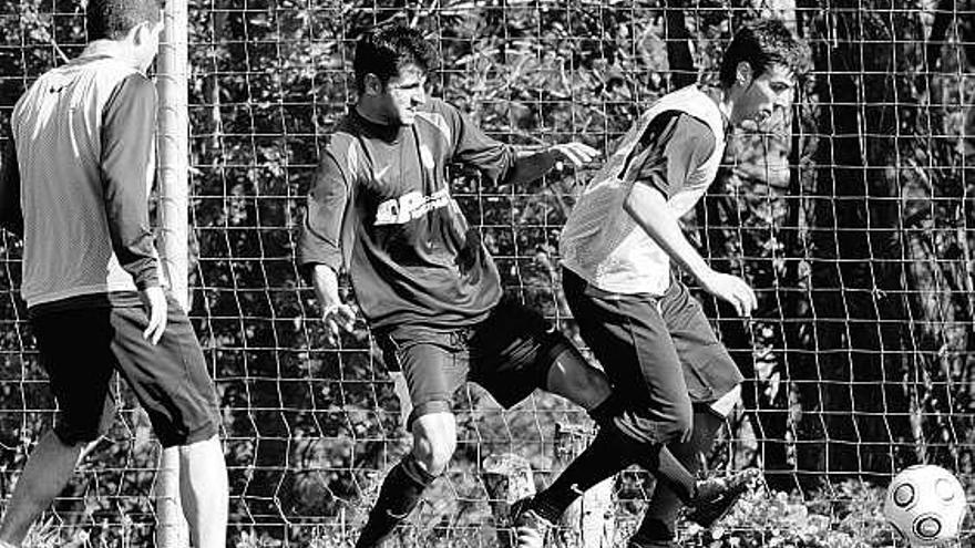 Ania disputa el balón a Rubén González, durante un entrenamiento, bajo la atenta mirada de Xavi Moré, a la izquierda.