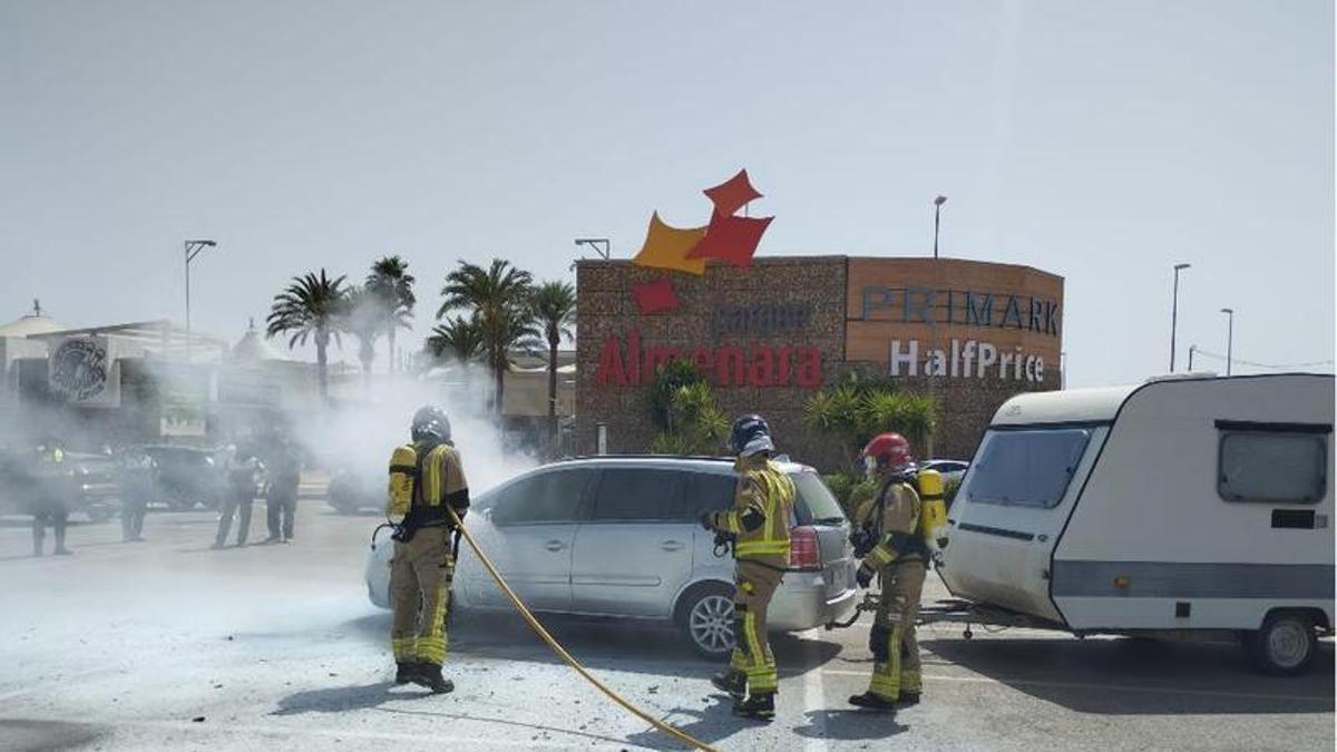 Los bomberos apagan el fuego de un coche en el parking abierto del Centro Comercial Almenara en Lorca.