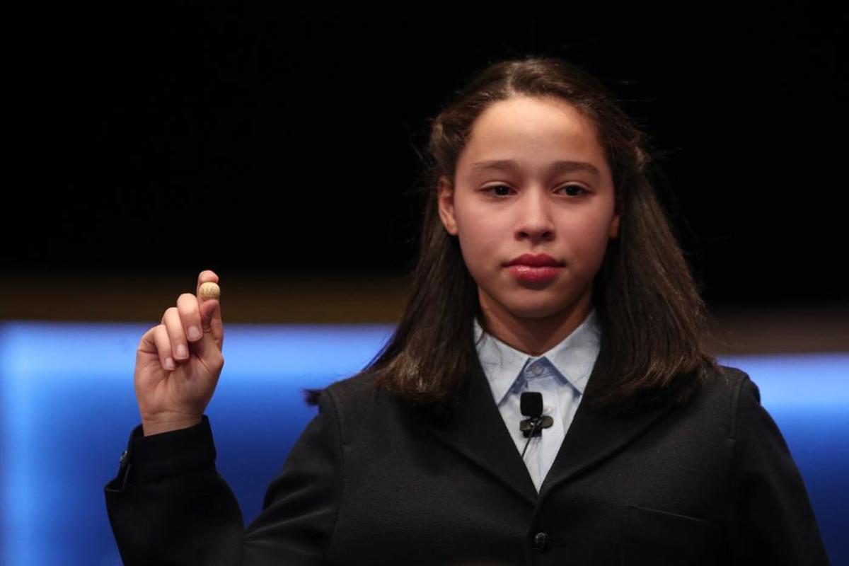 Una de las niñas de la residencia de San Ildefonso posa con la bola del Primer Premio de la Lotería de Navidad.