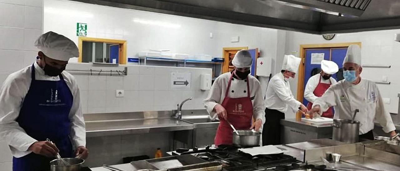 Alumnos de Hostelería de Llanes, ayer, cocinando en las dependencias del centro bajo la dirección del profesor Jaime Llano, primero por la derecha.  | Eva San Román