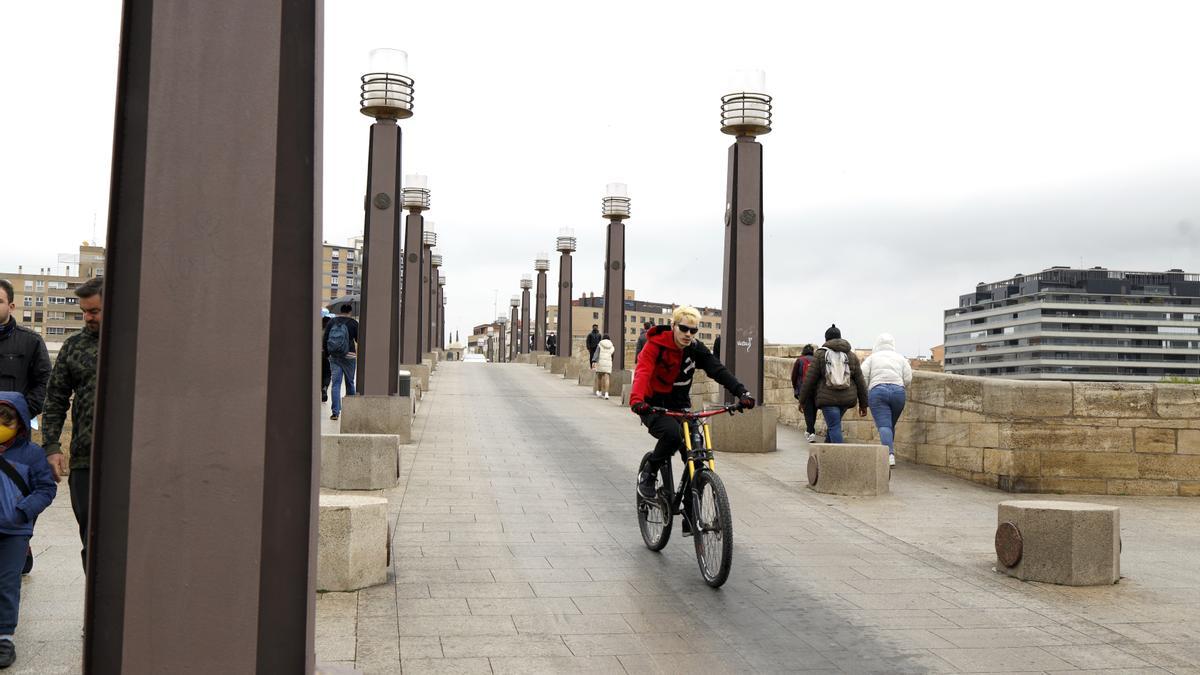 Un ciclista circula por el puente de Piedra de Zaragoza.