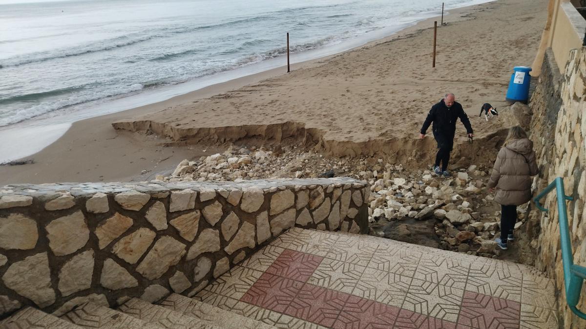 Dos vecinos acceden a la playa por un tramo destrozado