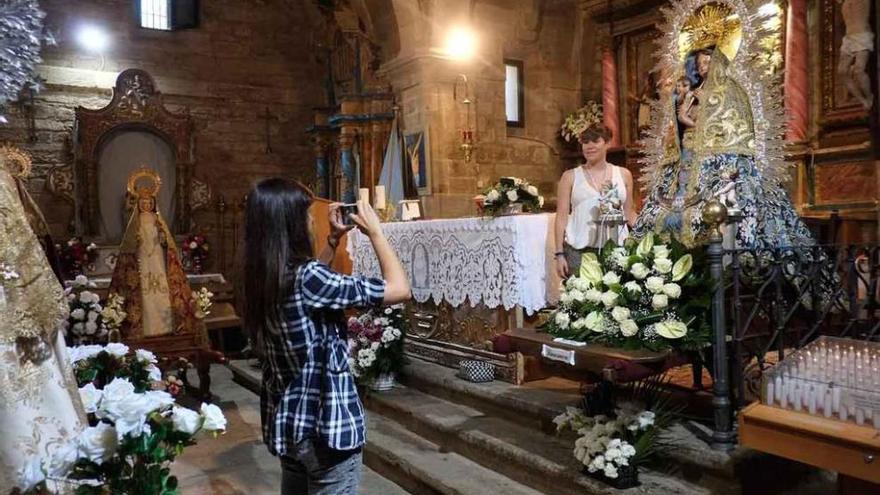 Una mujer toma una fotografía a otra junto a la Virgen de la Alcobilla