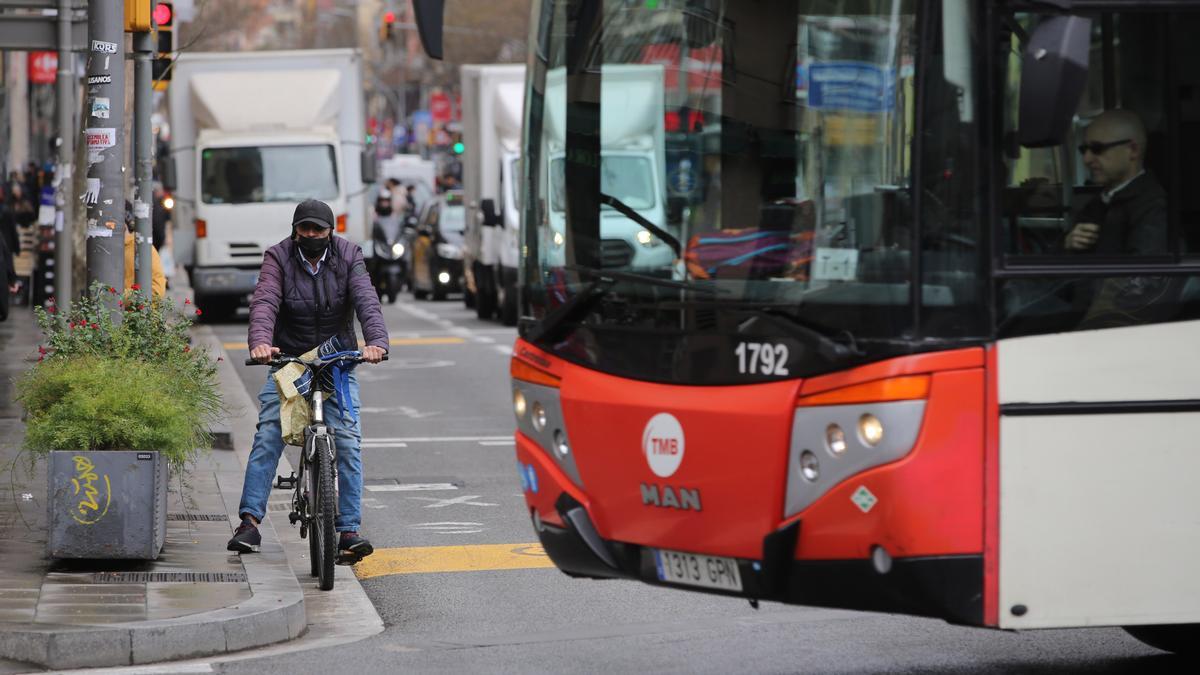 Una bici aguarda en uno de los cruces de la calle de Sants, en presencia de un vehículo de TMB en pleno giro