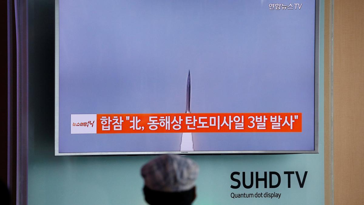 A passenger watches a TV screen broadcasting a news report on North Korea firing three ballistic missiles into the sea off its east coast, at a railway station in Seoul