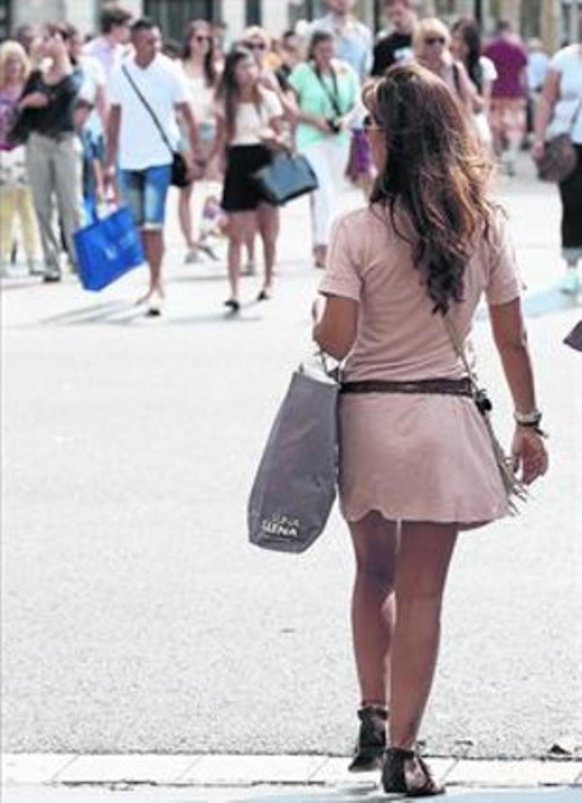 Una dona passeja per un carrer comercial de Barcelona al setembre.