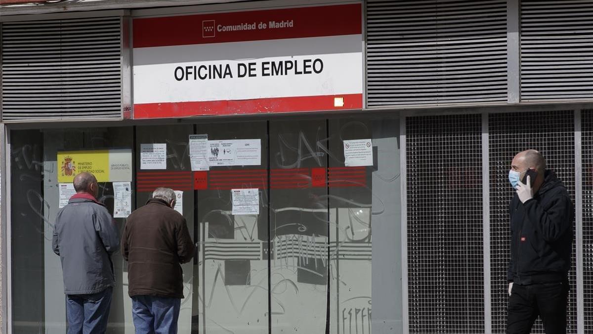 Dos personas leen los carteles de una oficina de empleo cerrada, el 16 de marzo del 2020