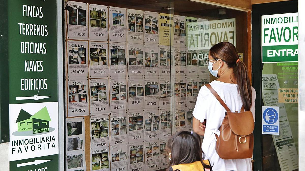 Una mujer y una niña observan anuncios inmobiliarios en un local de Vigo. |   // ALBA VILLAR