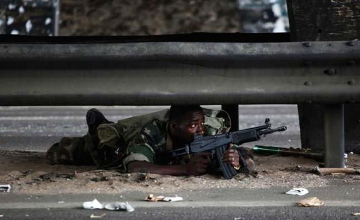 Un soldat lleial al president entrant de Costa d’Ivori, Alassane Ouattara, es resguarda del foc enemic estirat en una carretera d’Abidjan.