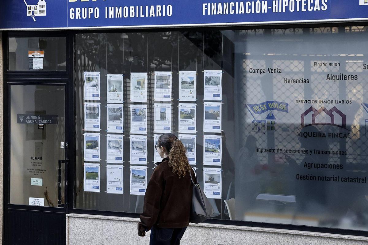 Una joven camina ante los anuncios expuestos en el escaparate de una inmobiliaria de Santiago