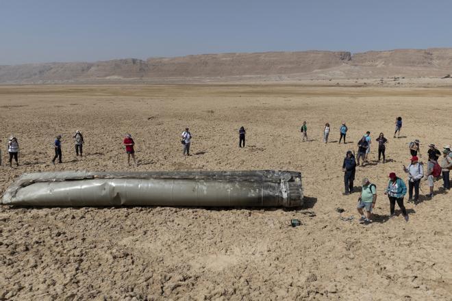 Gente congregada alrededor de parte de un misil balístico iraní interceptado cerca del Mar Muerto en Israel, el 20 de abril de 2024. 