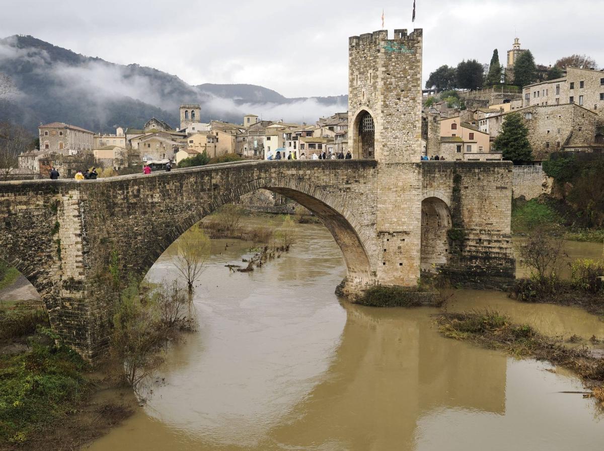 Imatges de la llevantada 1. El cabal del Fluvià al seu pas per Besalú, ahir al matí 2. El pantà de Susqueda desembassant aigua, en una imatge de TVE 3. Diverses persones contemplant l’estany intermitent d’Espolla, a Fontcoberta, que ha ressorgit per efecte de la llevantada 4. Un cotxe sense ocupants colgat per la neu a Setcases, en una imatge difosa ahir pels Bombers. | PERE DURAN / NORD MEDIA