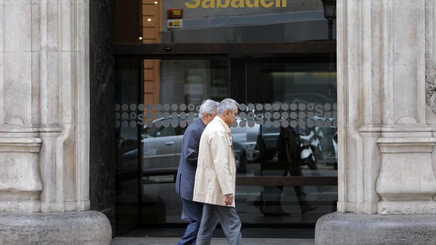 Dos ciudadanos pasan ante una oficina bancaria.