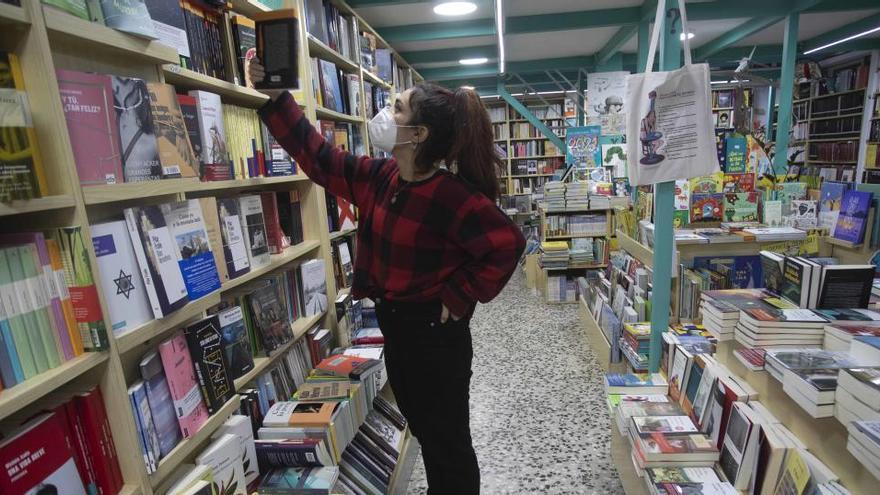 Una joven inspecciona las estantería de una librería de Valencia