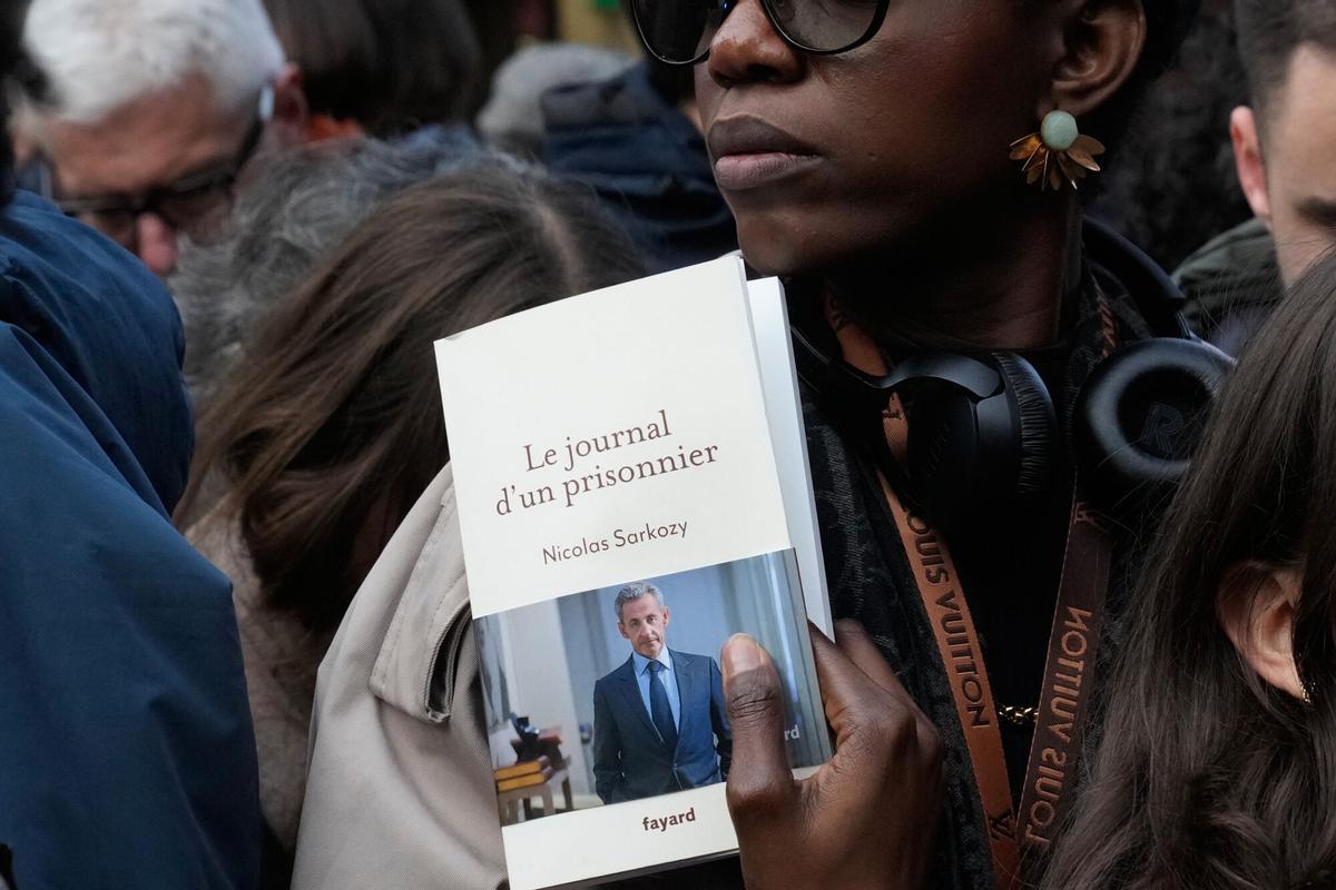 Una mujer muestra un ejemplar del libro de Sarkozy, este miércoles, frente a una librería de París.