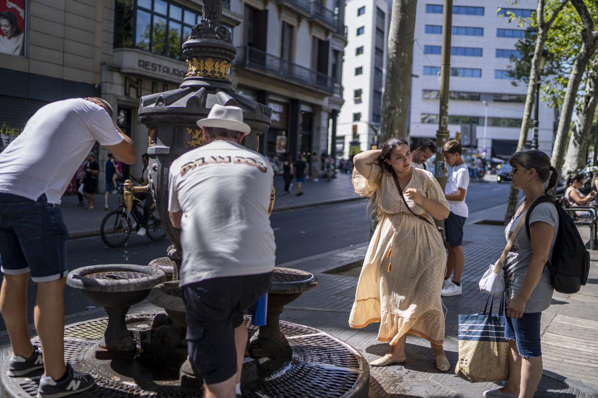 Diverses persones refrescant-se a la font de Canaletes de Barcelona.