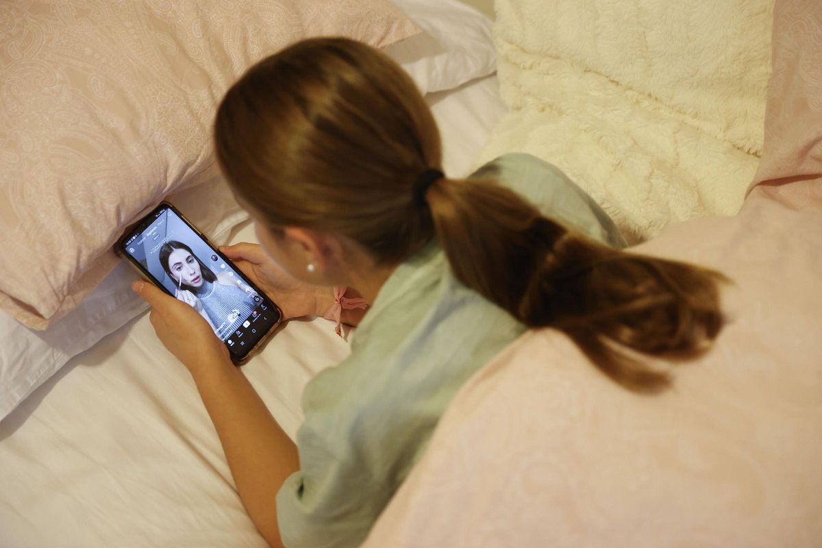 Una niña ve el móvil desde la cama.