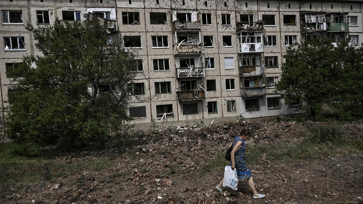 Una mujer pasa junto a un edificio residencial dañado tras combates y bombardeos cerca de Severodonetsk