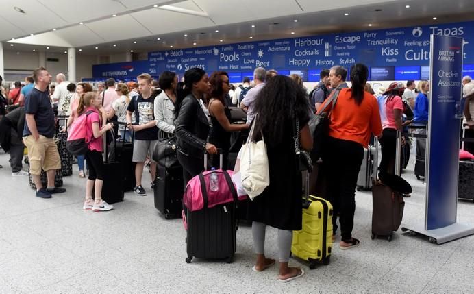 People queue with their luggage for the British ...