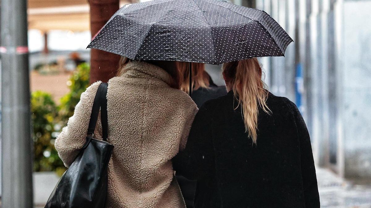 Dos mujeres se cubren de la lluvia en Santa Cruz de Tenerife con un paraguas.