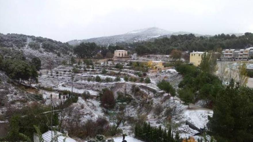 Dos personas creando un muñeco de nieve en un parque del barrio de la Zona Norte de Alcoy.