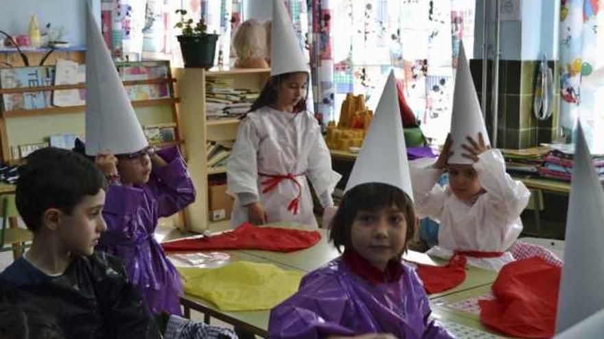 Niños y niñas, ayer en clase, preparan la vestimenta para convertirse en cofrades.