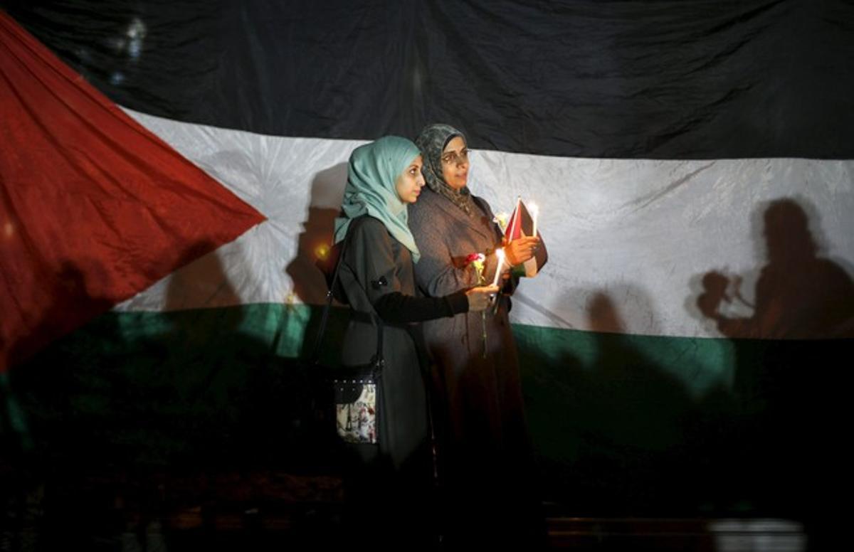 Women hold candles as they stand in front of a Palestinian flag during a rally to pay tribute to Palestinians who organizers said were killed recently by Israeli troops, on Christmas day in Gaza City December 25, 2015. REUTERS/Suhaib Salem