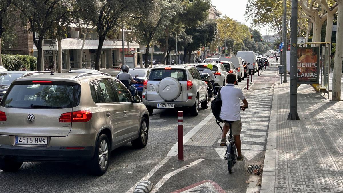 Una bici avanza por el carril ciclista de Via Augusta mientras los coches hacen cola entre Vergós y Mitre, este miércoles