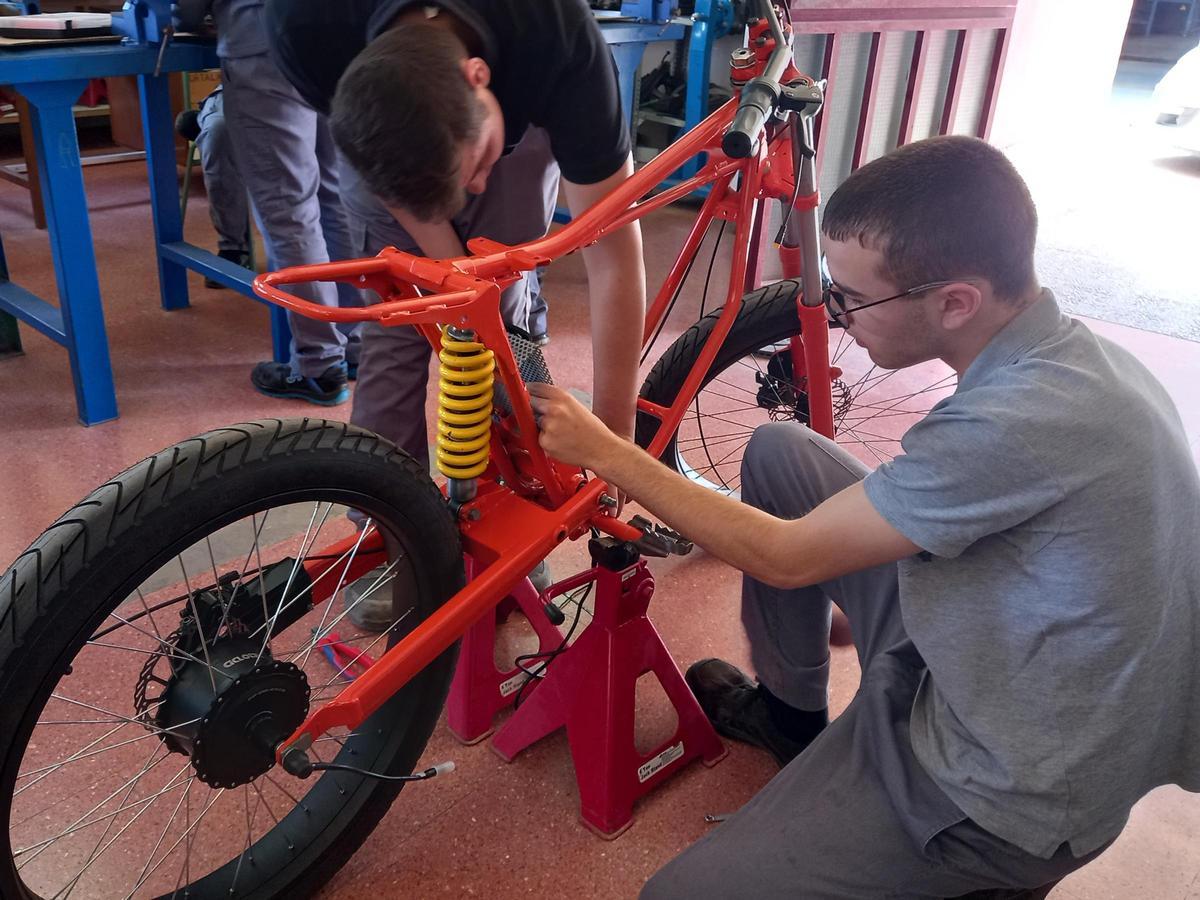 Un par de alumnos trabaja en el chasis de la motocicleta.