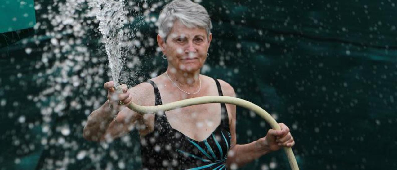 Una mujer, en Palmés, se refresca con una manguera.   | // IÑAKI OSORIO