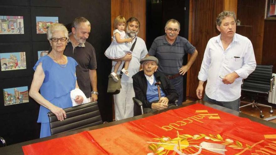 Dios Vázquez, su familia y el alcalde, ante la bandera que tejió su madre en los años treinta. // Santos Álvarez