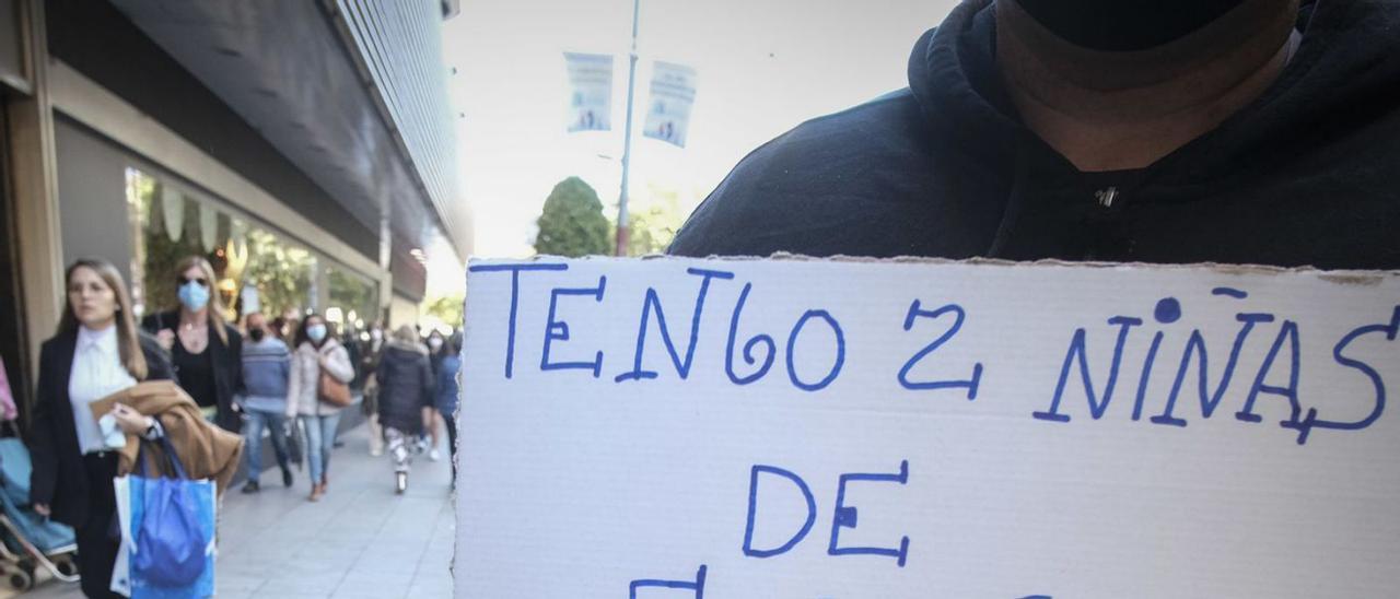 Un hombre pide ayuda, con un cártel, en la principal calle comercial de Alicante, esta semana.  | ÁXEL ÁLVAREZ