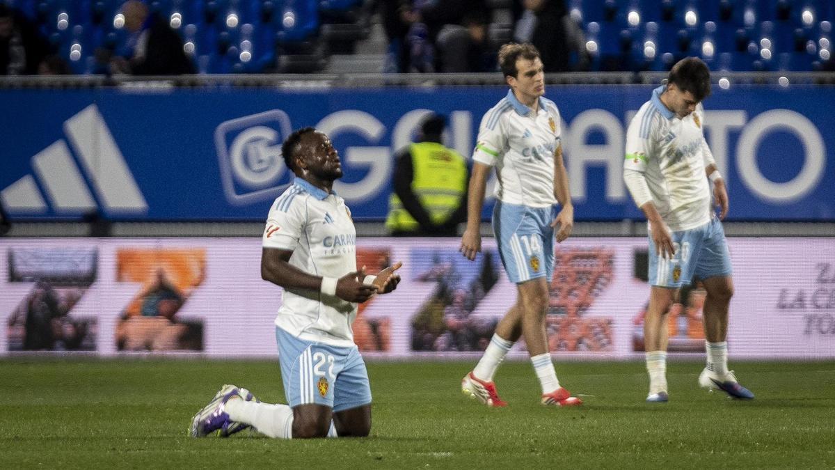 Agada, que debutó el sábado en el Zaragoza, reza al final del partido, con Francho y Aguirregabiria al lado.