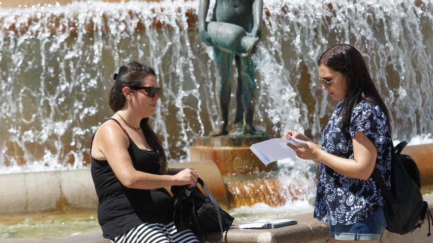 Dos turistas en la fuente de la plaza de la Virgen de València. Foto: Eduardo Ripoll