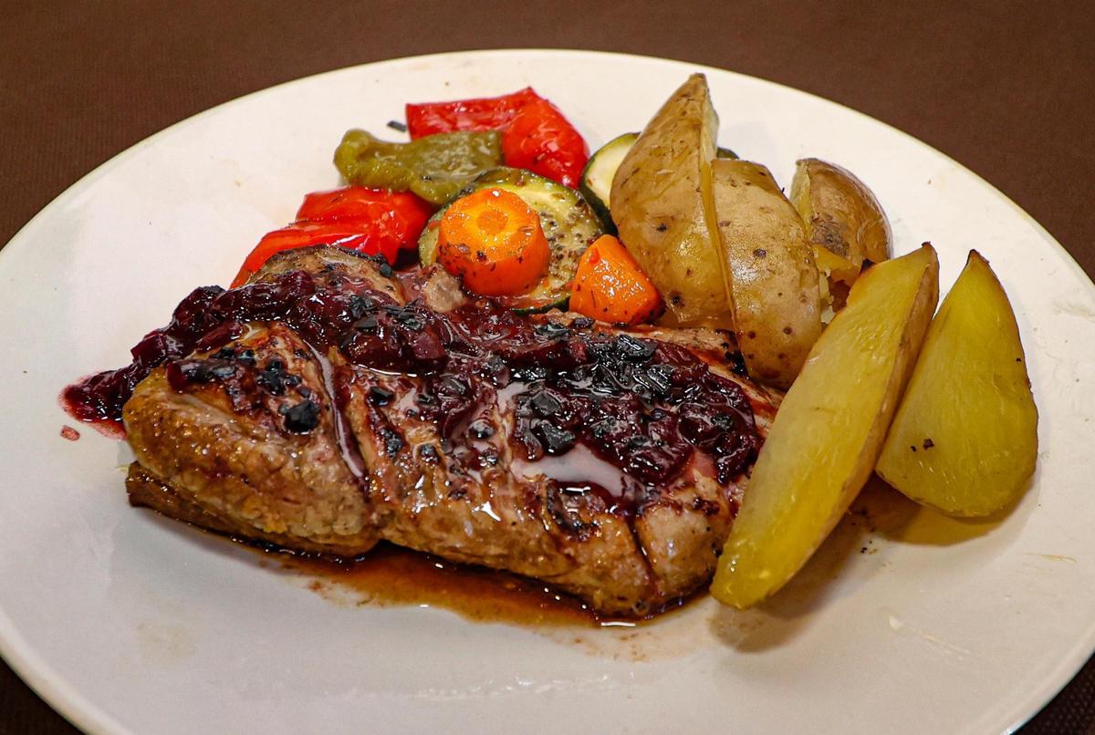 Secreto a la brasa con salsa de  cerezas al vino tinto.