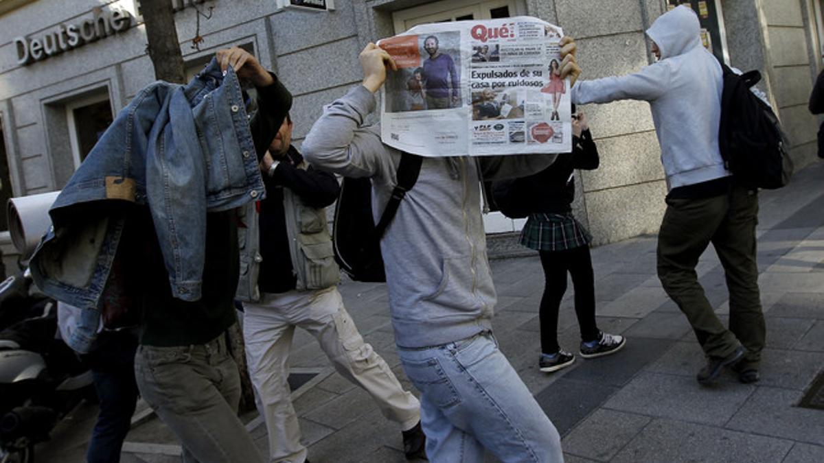 Uno de los indignados imputados por el bloqueo del Parlament se tapa con periódicos a su salida de la Audiencia Nacional, este martes.