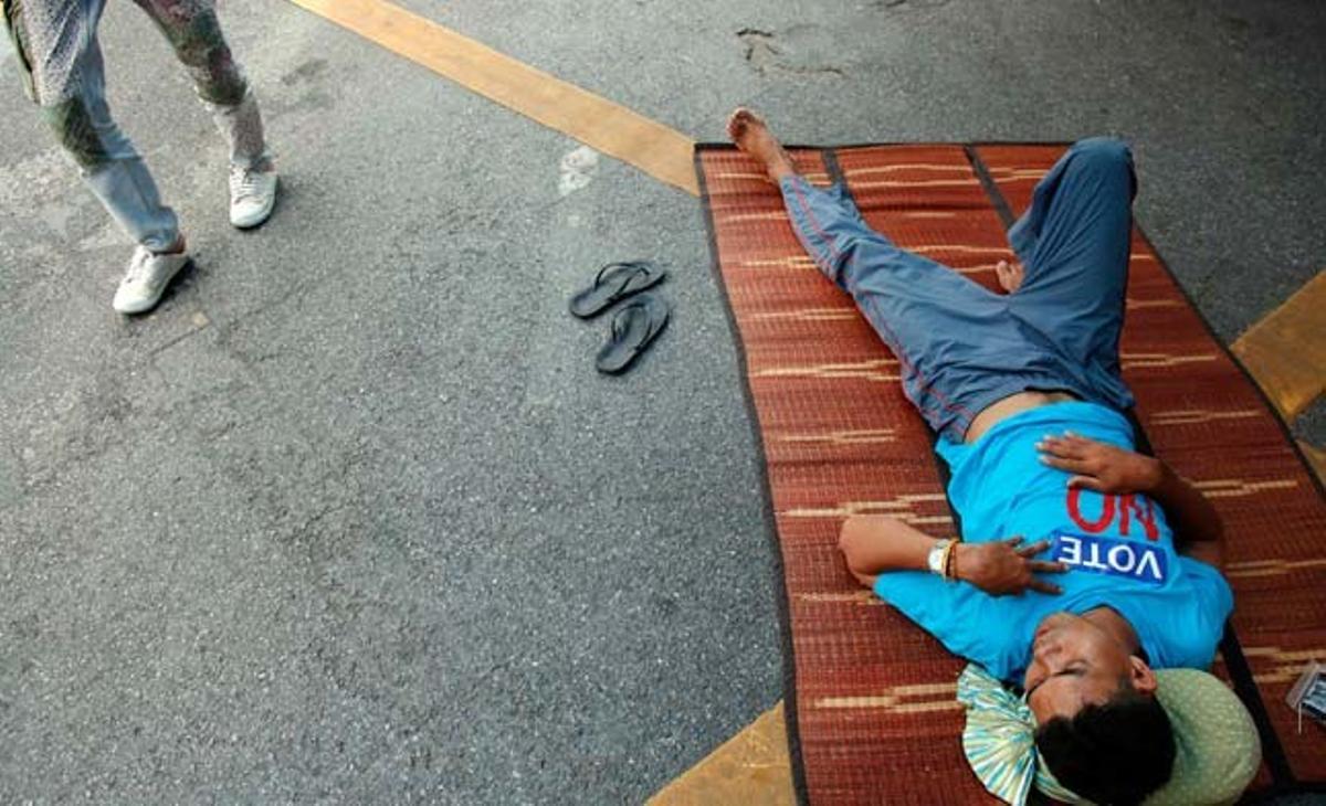 Un home amb una samarreta que anima a l’abstenció davant les pròximes eleccions a Tailàndia descansa a prop del palau del Govern a Bangkok.