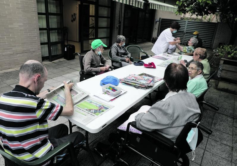 Andrés Armando, de espaldas, leyendo el periódico, junto a otros usuarios del Clara Ferrer en Gijón.  