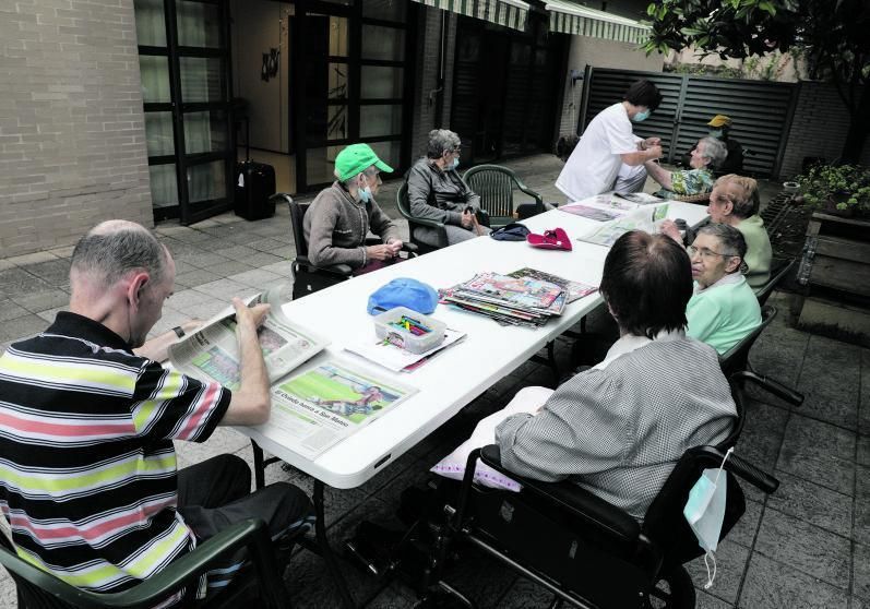 Andrés Armando, de espaldas, leyendo el periódico, junto a otros usuarios del Clara Ferrer en Gijón.