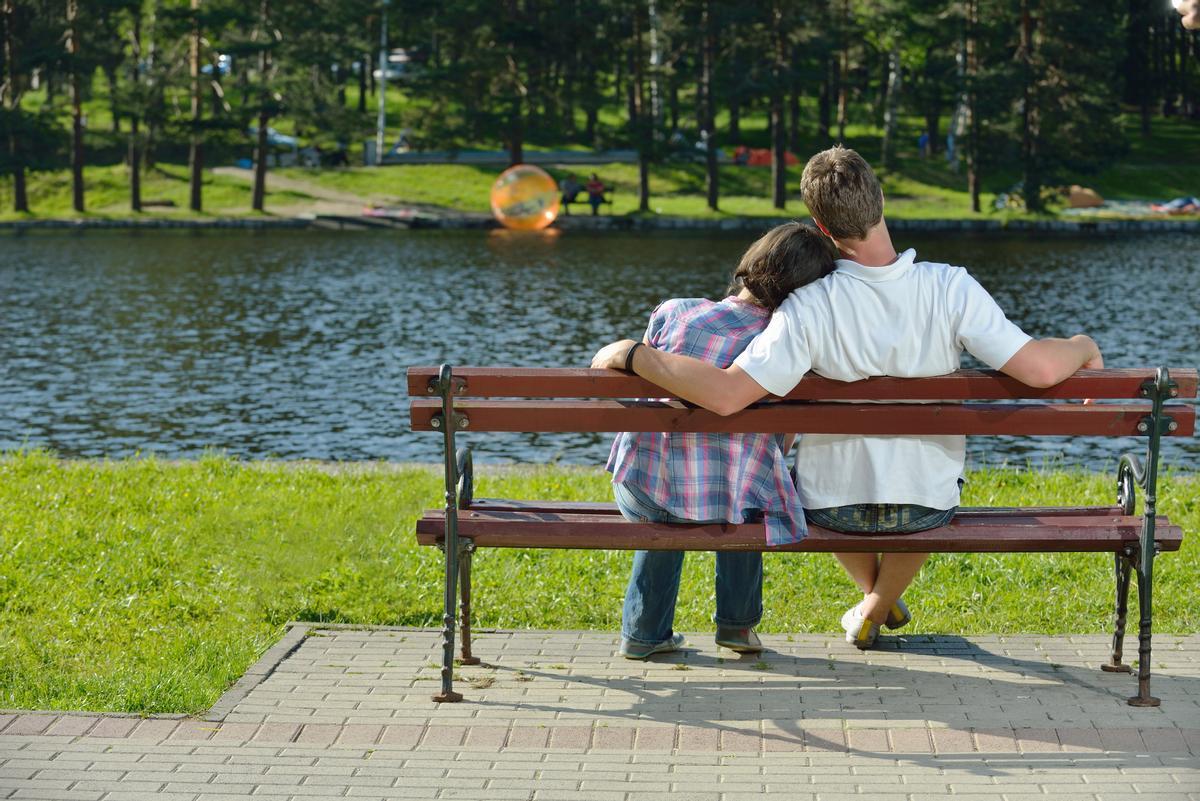 Una pareja de adolescentes, en el banco de un parque.