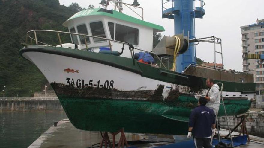 Los pescadores del «Abelán», limpiando, ayer, los restos de galipote del casco de su lancha.